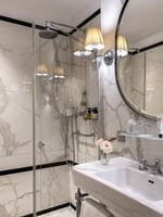 Superior Single Room bathroom featuring a marble vanity with mirror by the glass shower at HHotel Westminster Paris