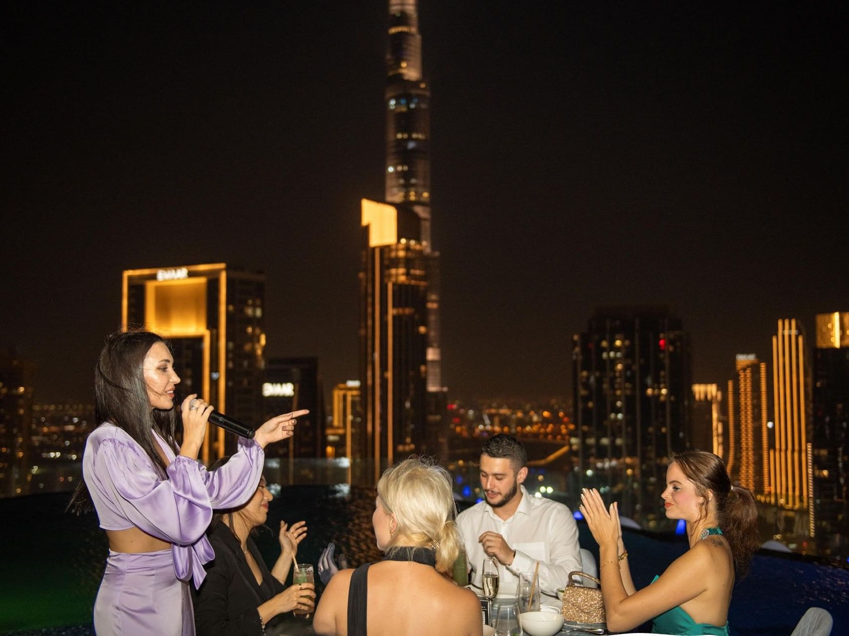 Woman singing to seated guests during the Ladies Night at Malibu Sky Lounge & Bar, one of the best rooftop lounges in Dubai