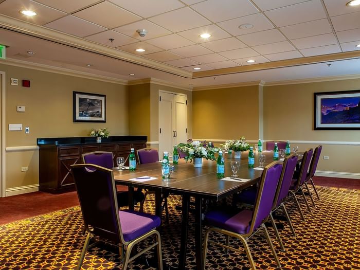 Long wooden table with purple chairs and water bottles under warm ceiling lights in Evans at Warwick Denver