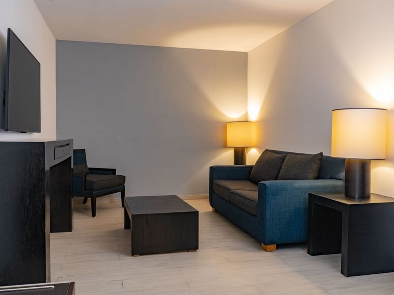 Living area with couch, chairs, TV and floor lamps in Prime Suite