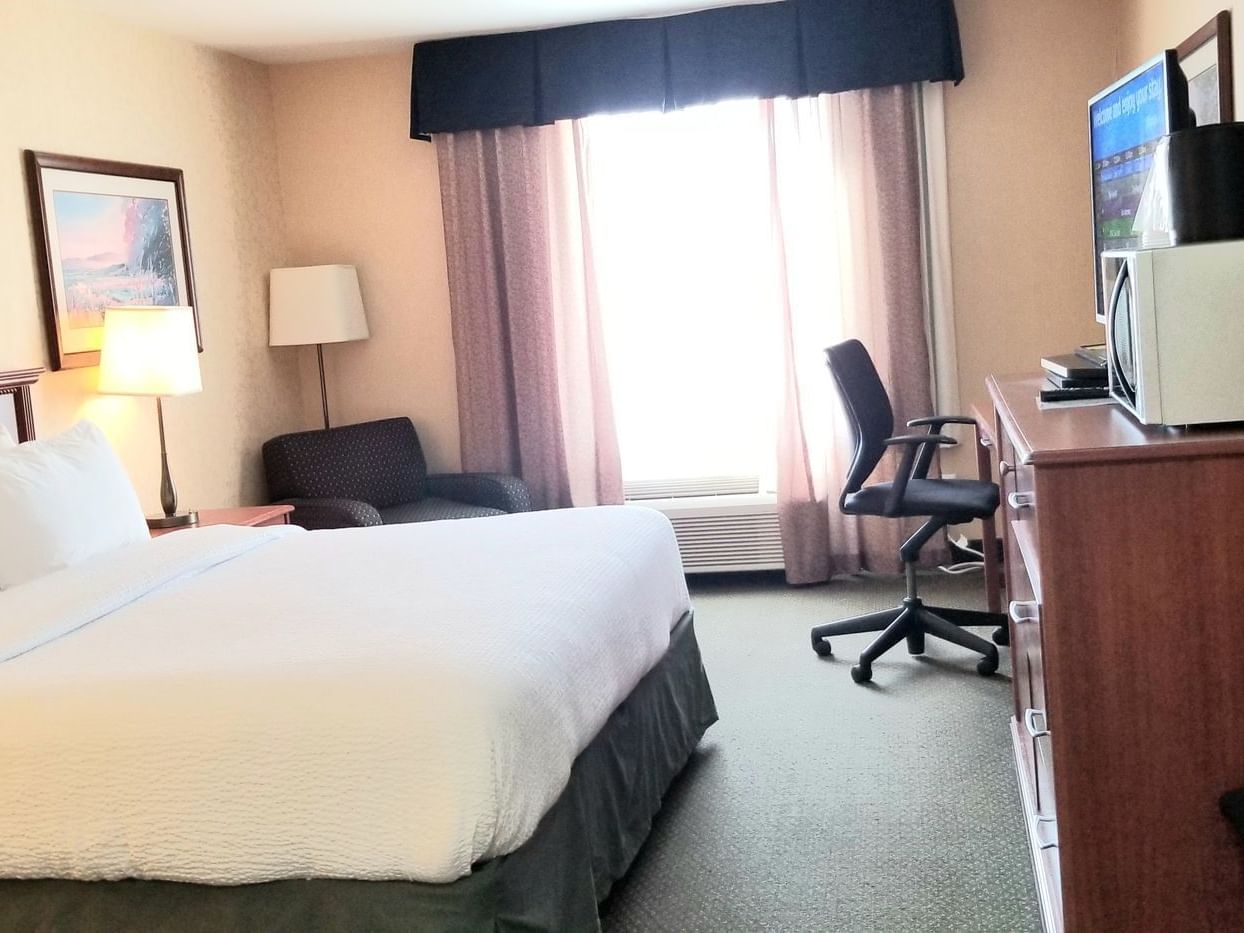 Work desk & lounger by bed in Standard One King at Merit Hotel & Suites, Fort McMurray