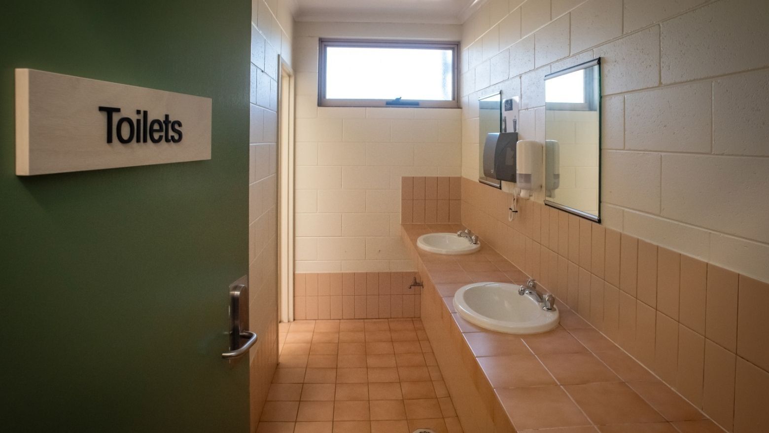 Entrance to a public restroom with two sinks and a window at La Trobe University.
