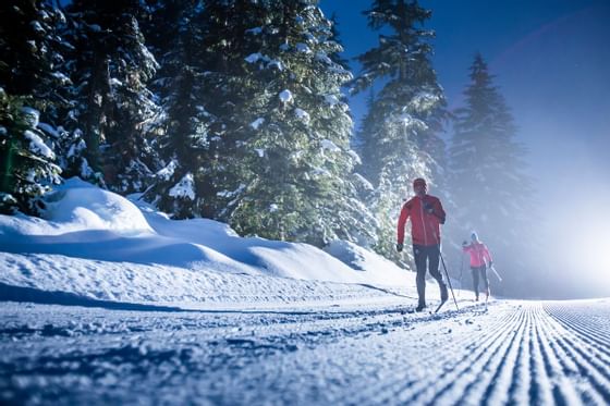 Two skiers gliding on a snowy trail during cross country skiing near Blackcomb Springs Suites