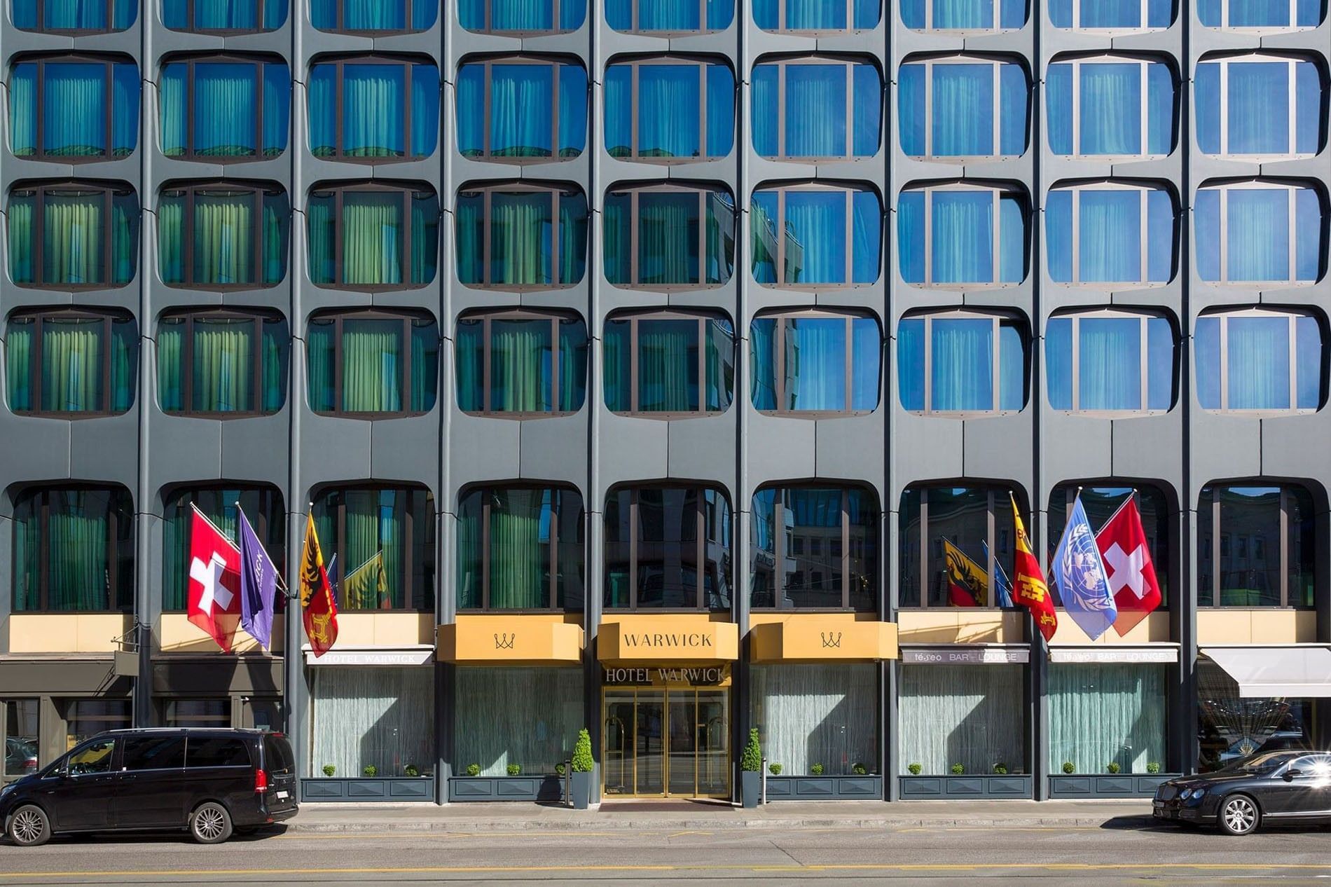 Exterior of Hotel Warwick Geneva by a city street under rows of windows