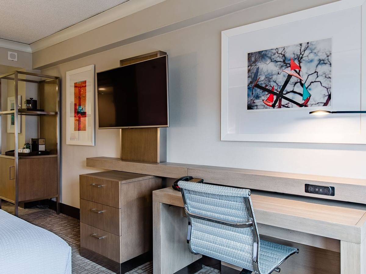 Hotel guestroom with king bed, TV, and desk