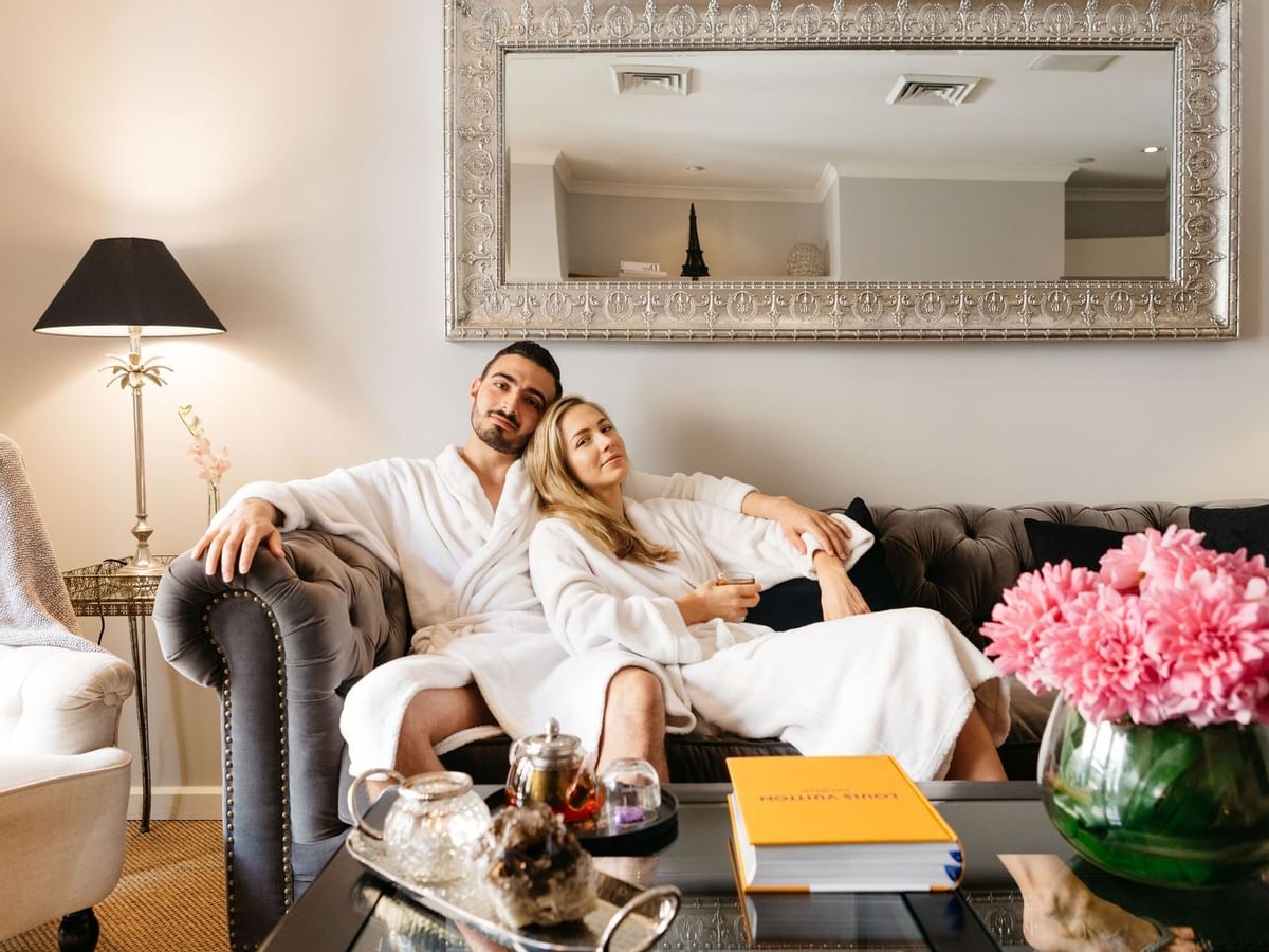 Two people in robes lounging on a couch in Stephanies Spa with elegant decor at Sofitel Brisbane Central