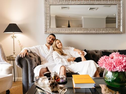 Two people in robes lounging on a couch in Stephanies Spa with elegant decor at Sofitel Brisbane Central