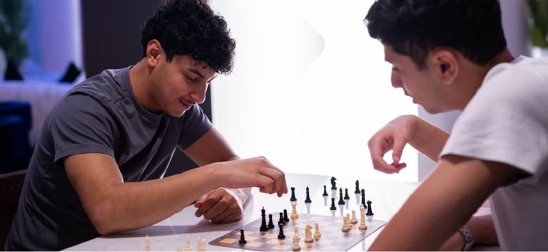 Friends engaged in a chess match creating memorable leisure time in Level Up - Indoor Gaming Hub at DAMAC Maison Aykon City