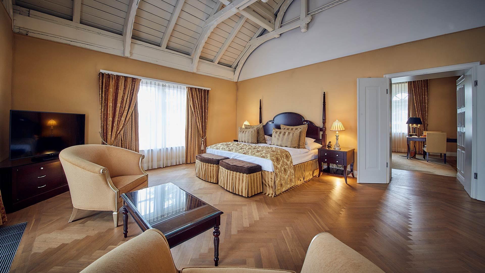 Interior of a Suite with wooden floors and a king bed at Falkensteiner Schlosshotel Velden