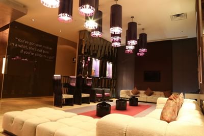 Cream sectional sofas and black cylinder pendant lights near guitar displays in the lobby at Megapolis Hotel Panama