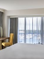 King bed by a wooden desk with a yellow chair in One Bedroom Harbourfront Suite at Warwick Paradise Island Bahamas