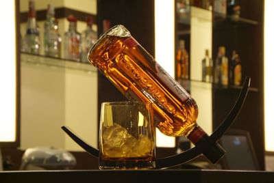 Whiskey bottle and glass placed on a table in Neo Café at Amora Neoluxe Hotel Bangkok
