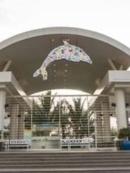 Aquarium entrance with a dolphin logo by stone steps under a curved roof near Warwick Jeddah Hotel & Spa