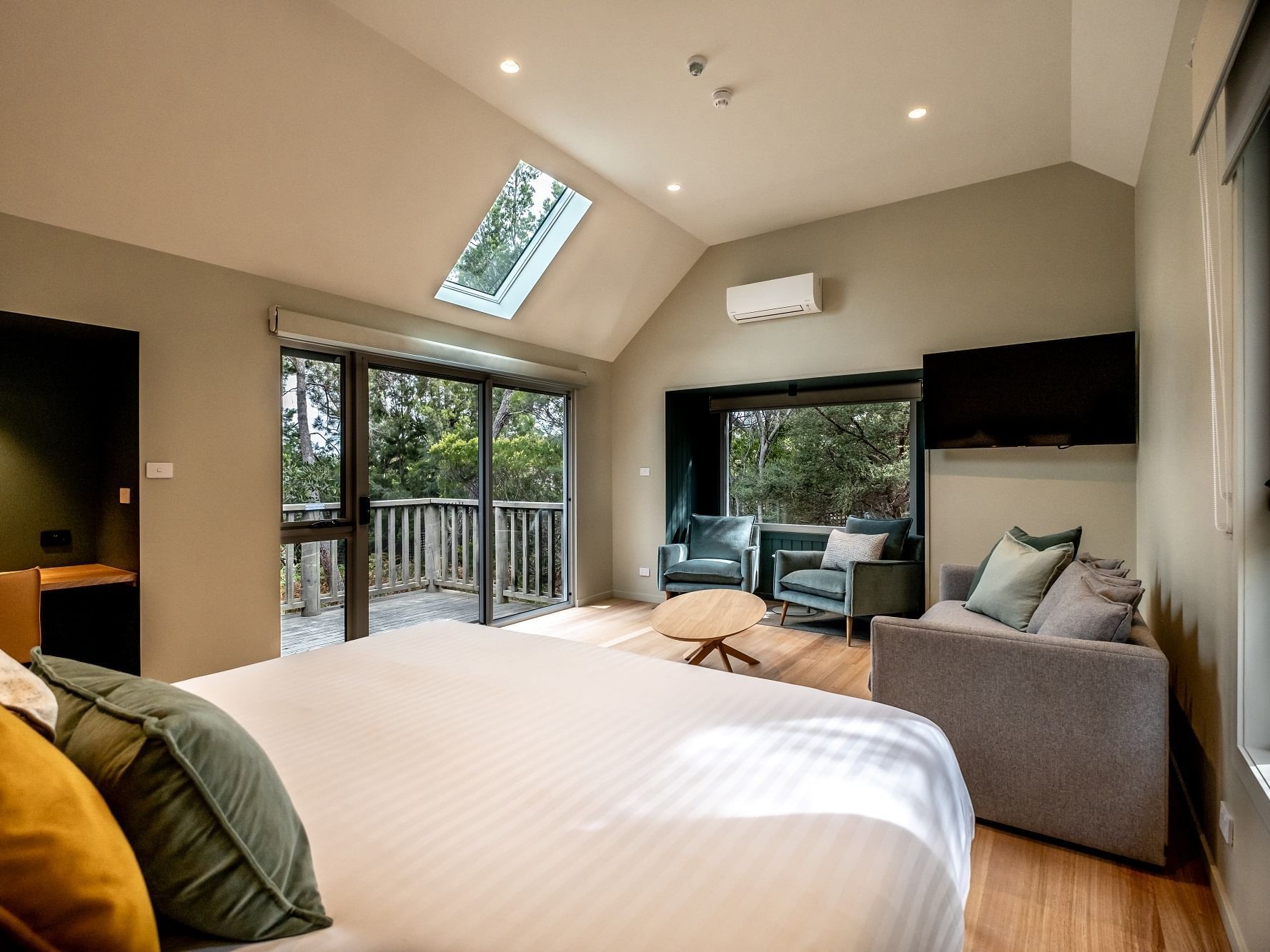 TV & lounge area facing the cozy bed in Bushland Cabin with wooden floors at Freycinet Lodge