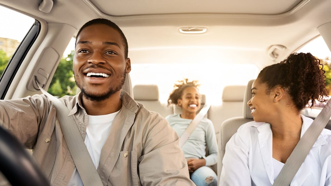 Family smiling in a car during a road trip.