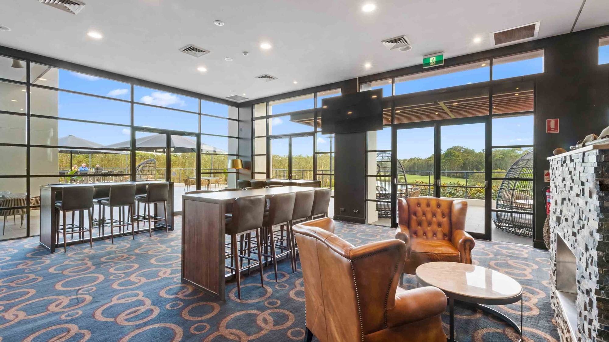 Wine Bar with stools, leather chairs, and large windows overlooking the golf course at Mercure Kooindah Waters