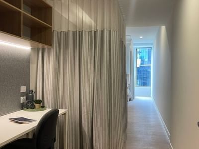 Modern room with desk, chair, curtained divider, and bright hallway within a 4 Bedroom Twin Share Apartment at UniLodge Brisbane City.