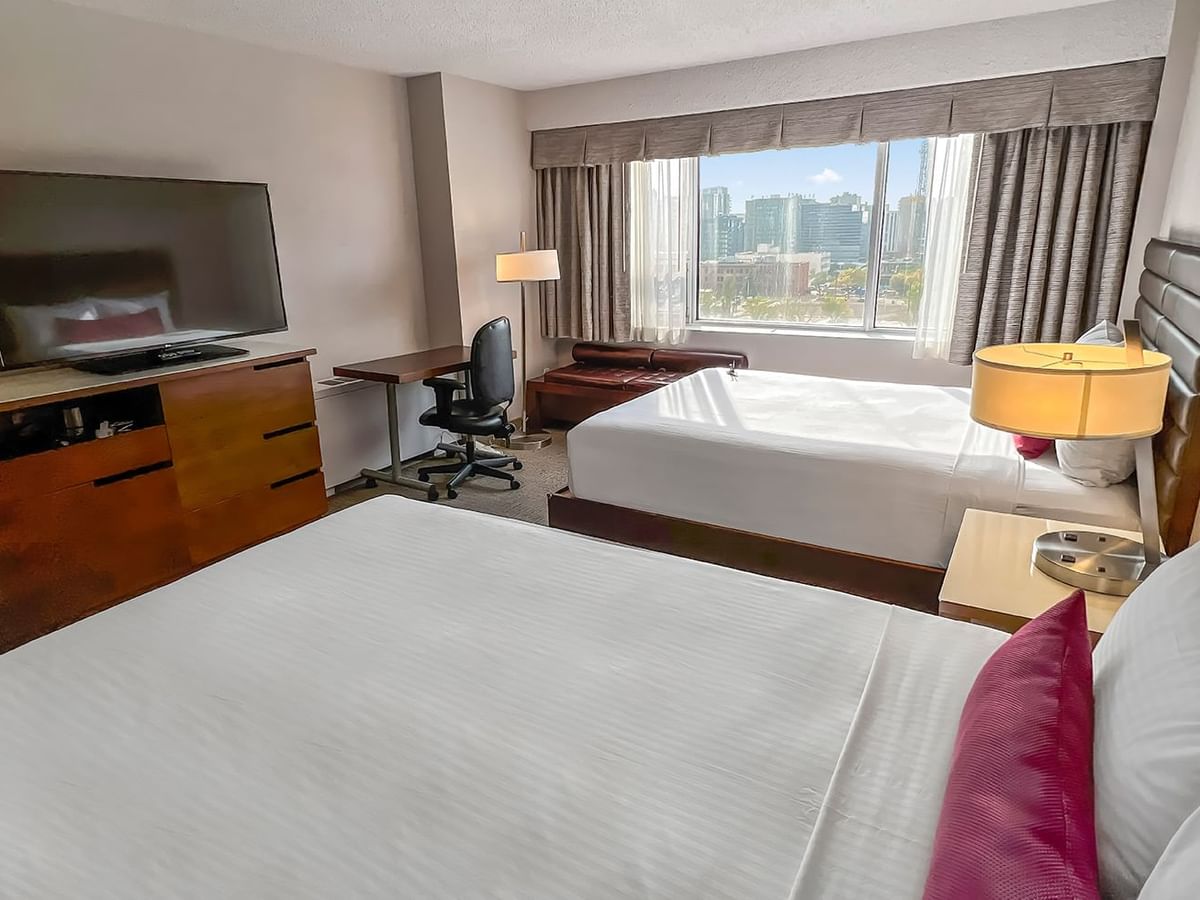 Hotel bedroom with two queen beds, work desk, and TV