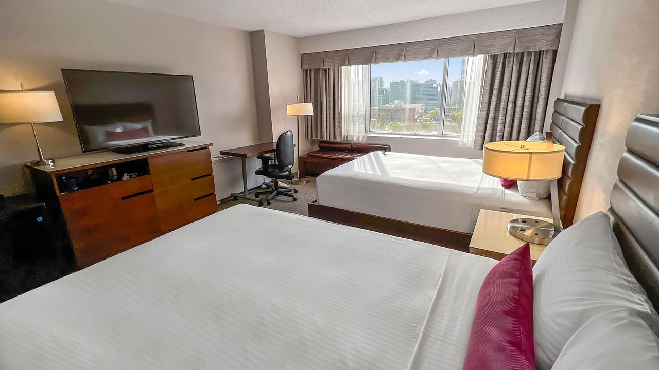Hotel bedroom with two queen beds, work desk, and TV