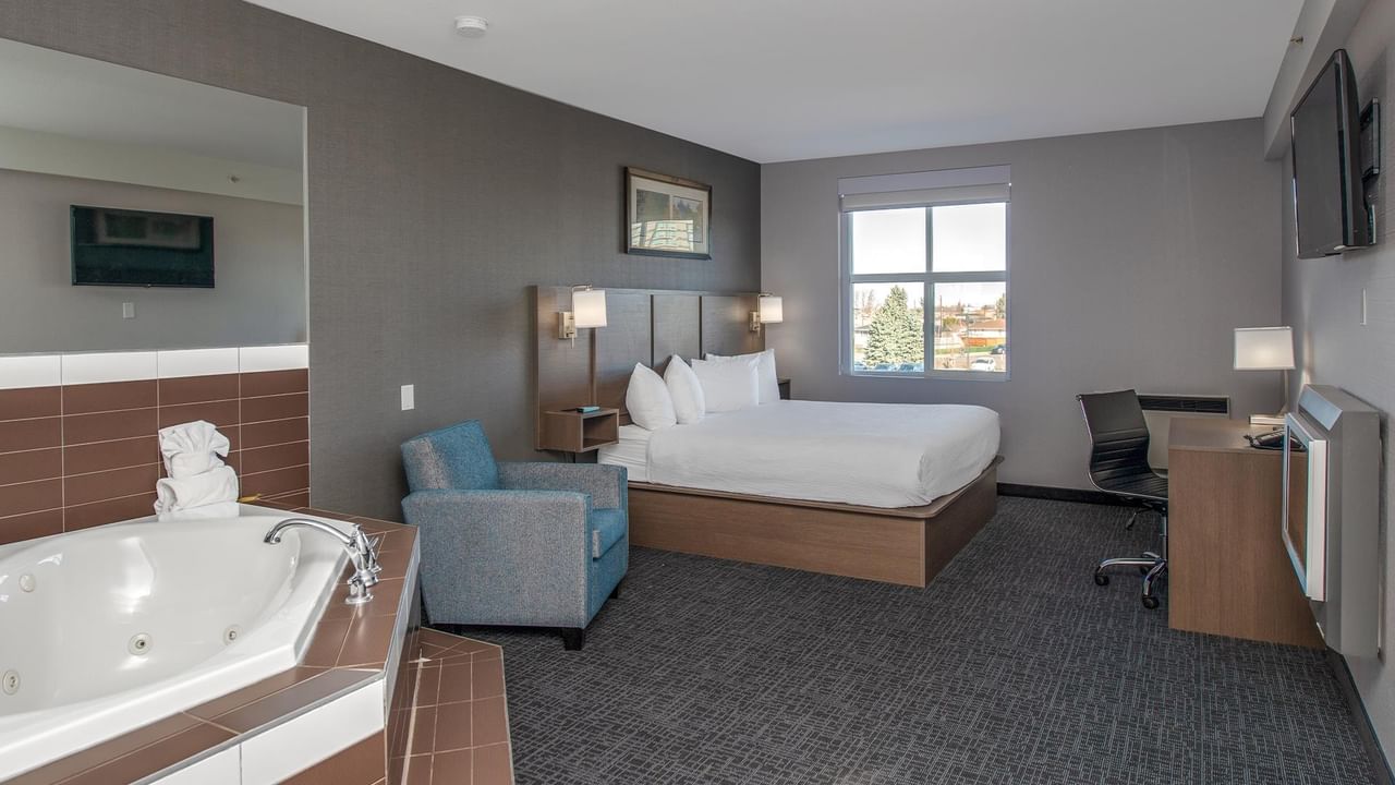 Room with bed, jetted tub, desk, and chair.