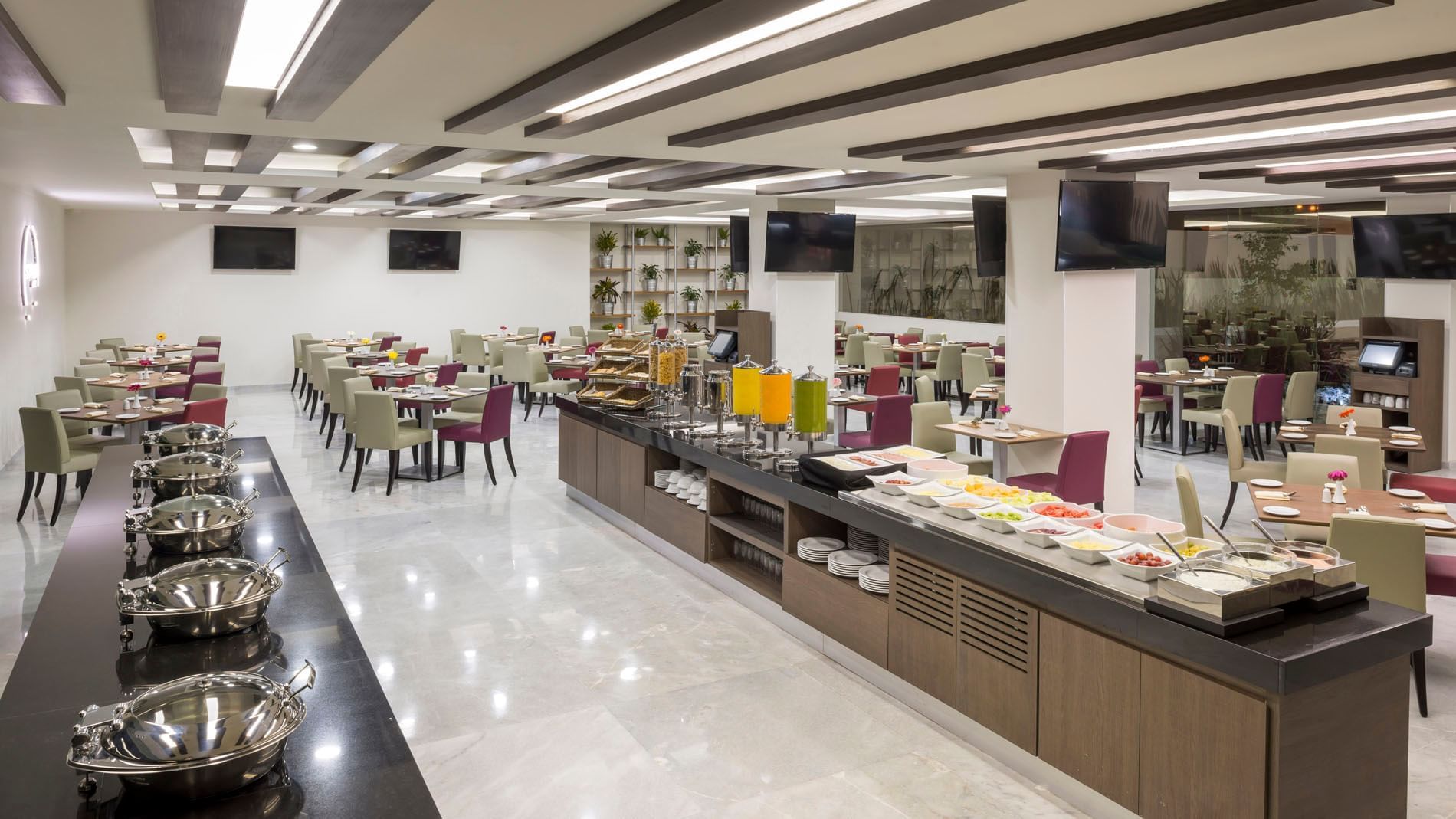 Modern breakfast buffet in Stock Cafe featuring fresh fruit, juice dispensers, and organized seating at Real Inn Celaya
