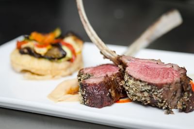 Roasted rack of lamb with a side of vegetables served elegantly in a restaurant at The Stanley Hotel