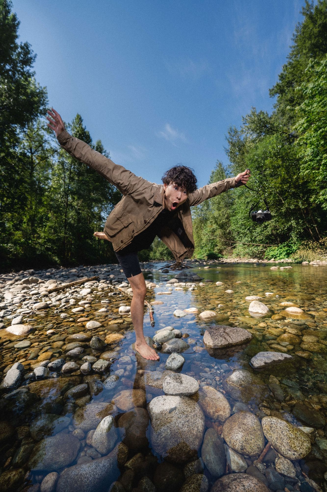 Young asian man standing on a rock situated in a British Columbian River