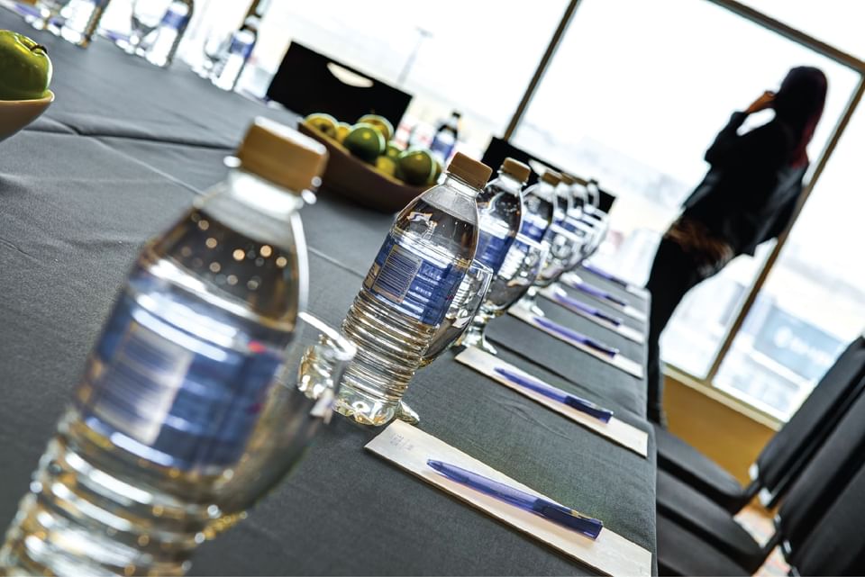 A table with water bottles and fruit arranged neatly on it at Hotel Clique Calgary Airport