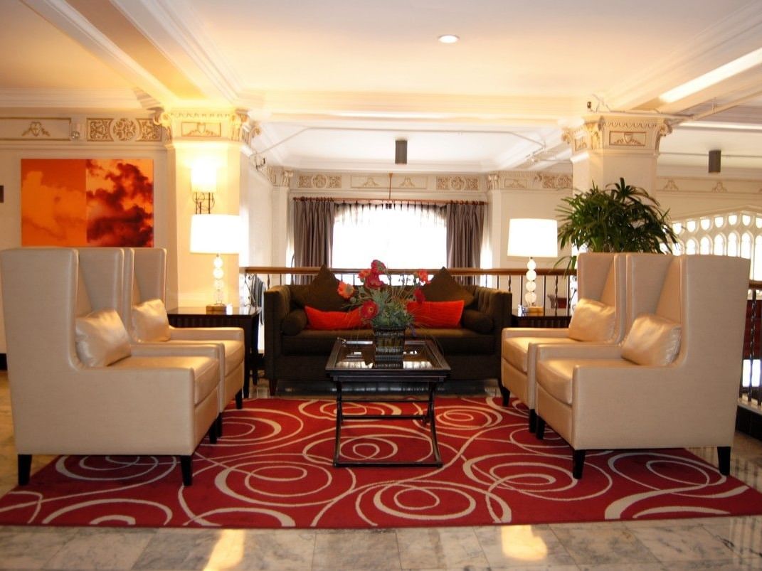 Elegant lounge area with couches, chairs, and a coffee table on a red rug at Pickwick San Francisco.