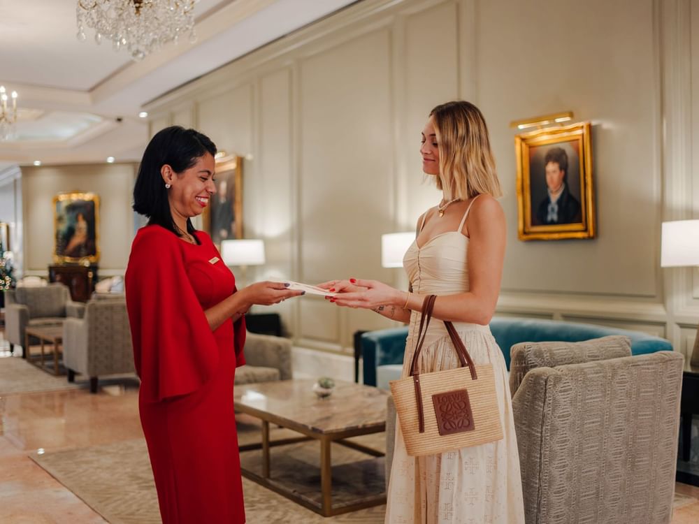 Hotel staff member handing a leaflet to a woman at Kempinski Hotel Cancún