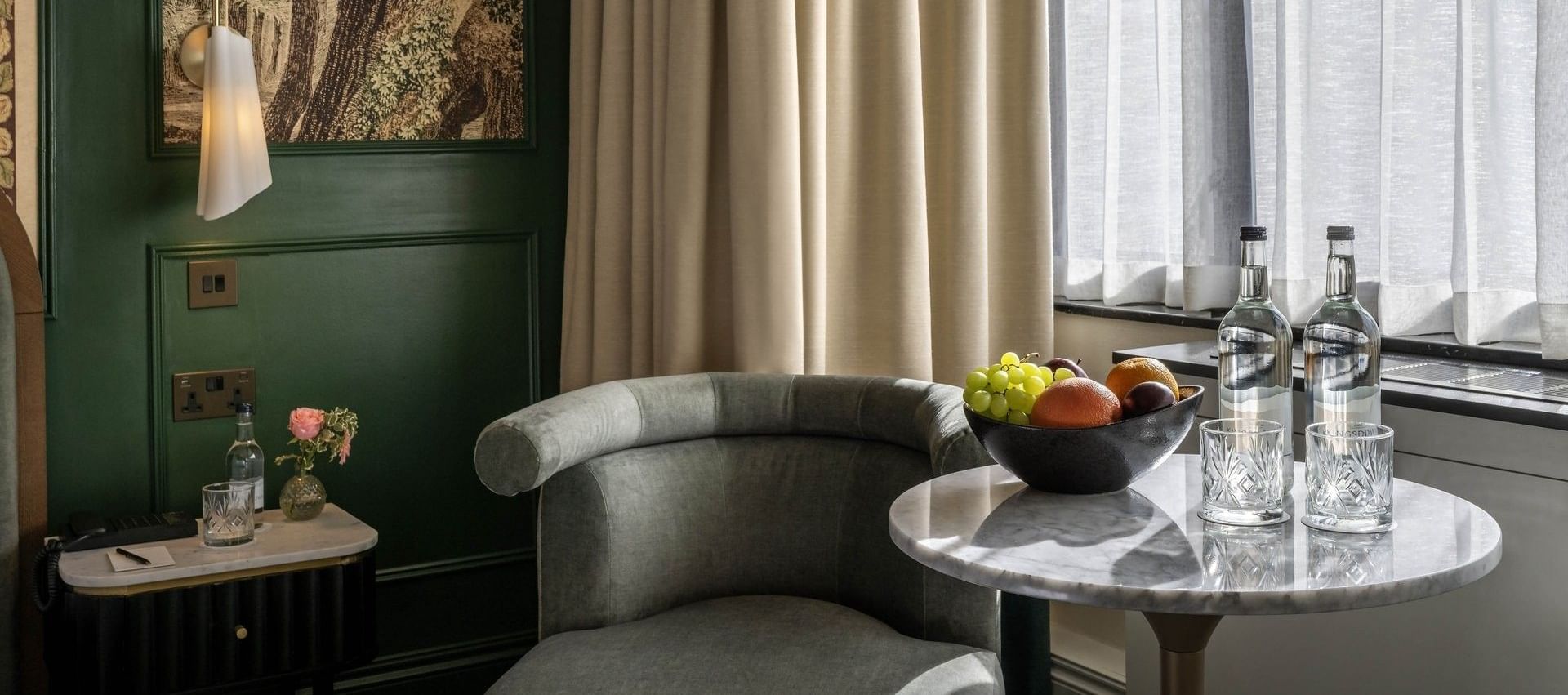 Armchair by a marble table under hanging art in Executive King at The Capital Hotel, Apartments and Townhouse