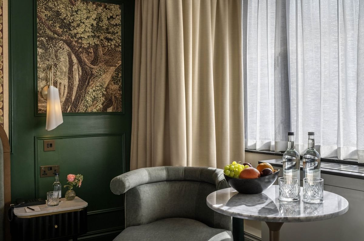 Armchair by a marble table under hanging art in Executive King at The Capital Hotel, Apartments and Townhouse