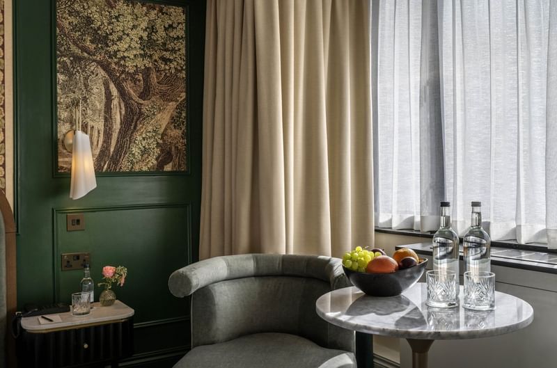 Armchair by a marble table under hanging art in Executive King at The Capital Hotel, Apartments and Townhouse