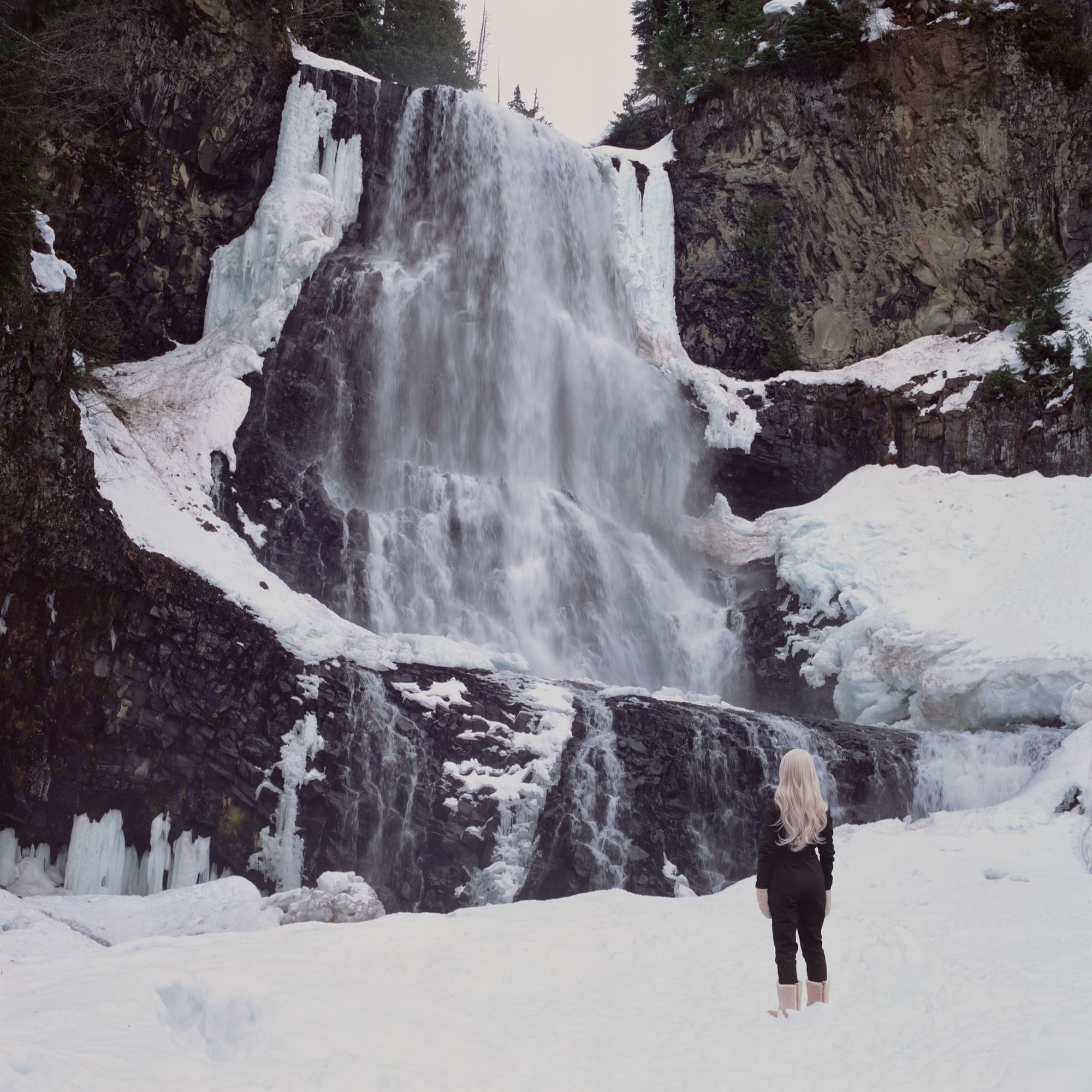 Woman standing in front of a waterfall in an icy winter