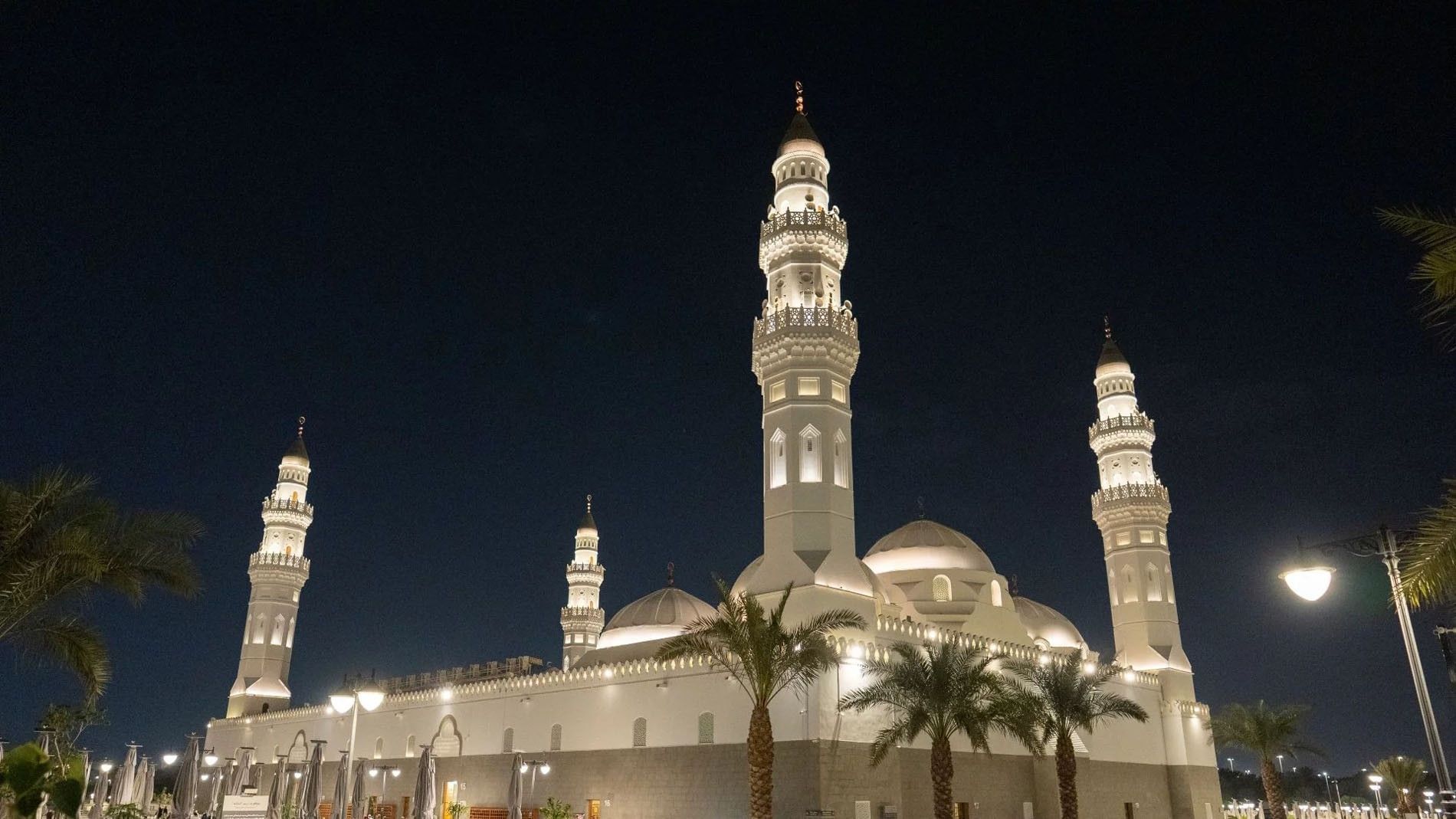 The Quba Mosque in Medina illuminated at night with white domes and tall twin minarets at Saja Warwick Madinah