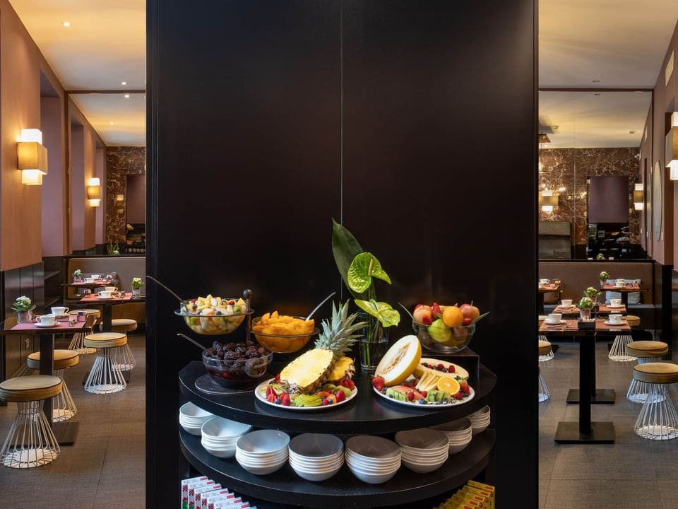 Fruit buffet with bowls of melon, pineapple, and grapes in the stylish Breakfast's dining area at The Guardian Hotel