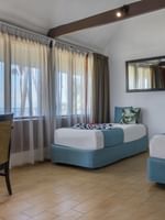 Two beds and chair in Beach Front Bure at Tambua Sands Beach Resort in Sigatoka