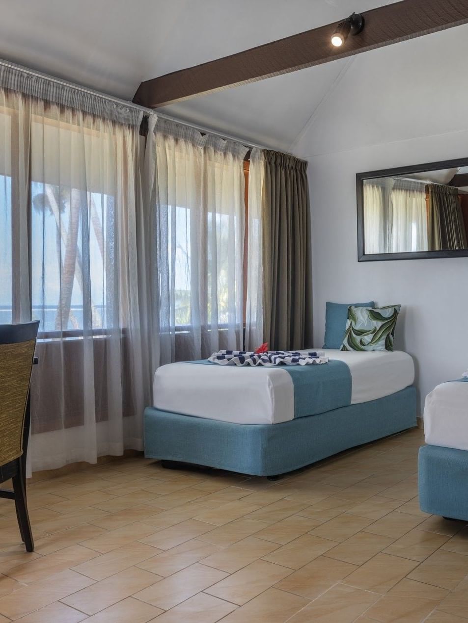 Two beds and chair in Beach Front Bure at Tambua Sands Beach Resort in Sigatoka.