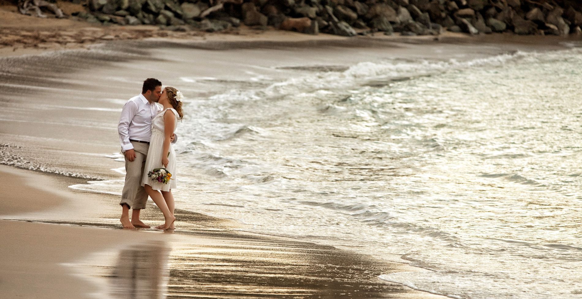 A wedding couple kissing on Whistle Beach near Buccaneer Hotel