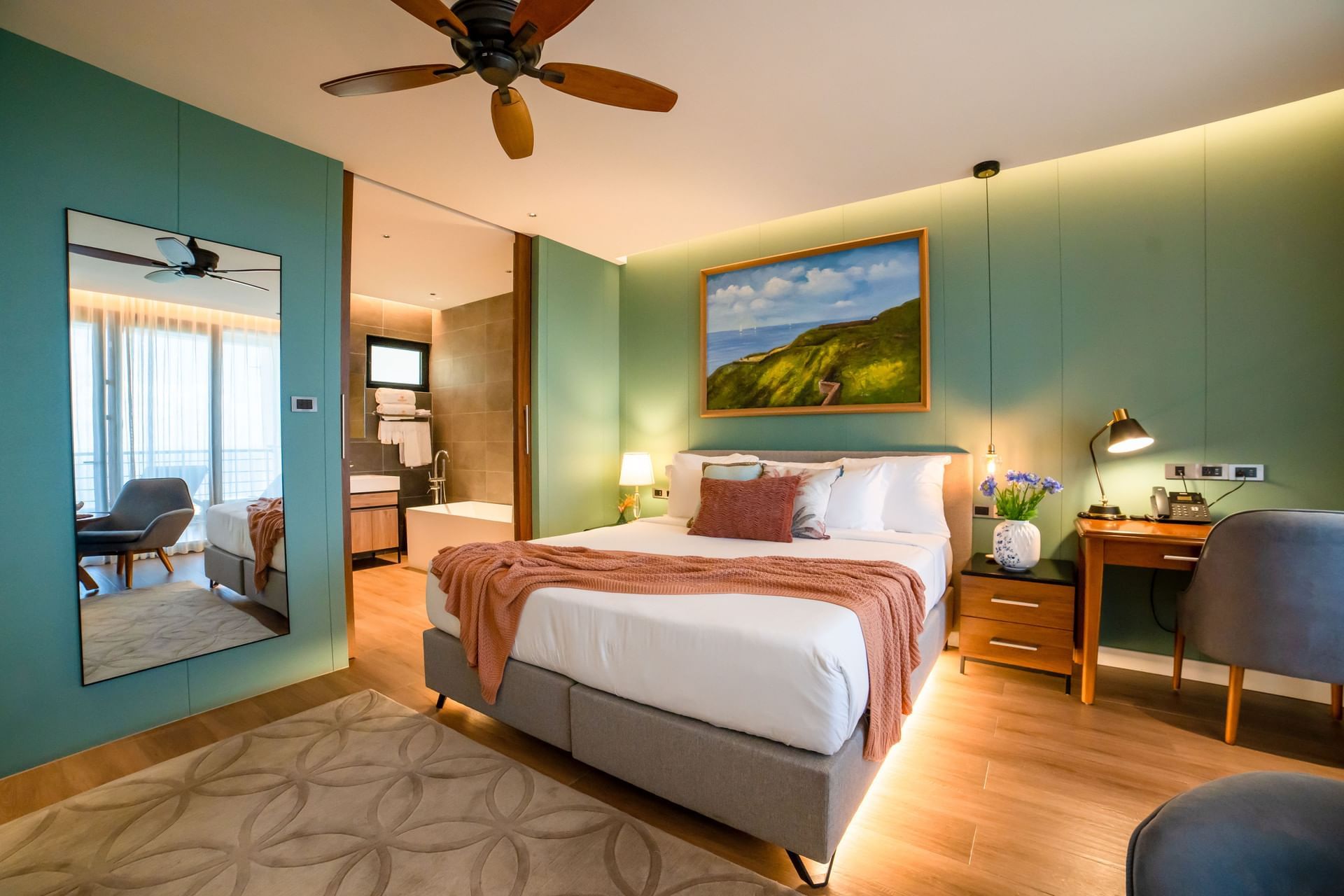 Werkruimte en zithoek bij het bed in Deluxe Ocean View Room met houten vloer bij Golden Rock Resort