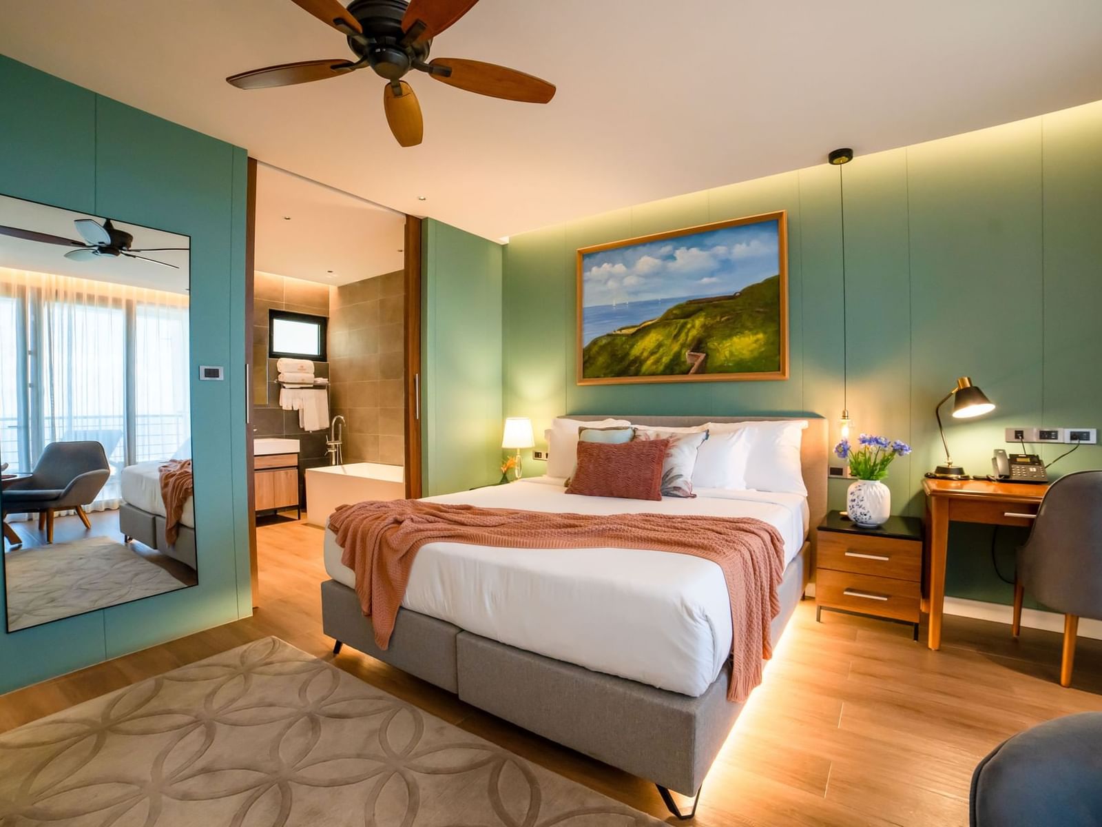 Workspace and seating area by the bed in Deluxe Ocean View Room with wooden floors at Golden Rock Resort