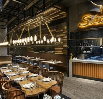 Beef Grill Club, Titanic Deluxe Lara’da uzun masalı ve sandalyeli şık restoran.