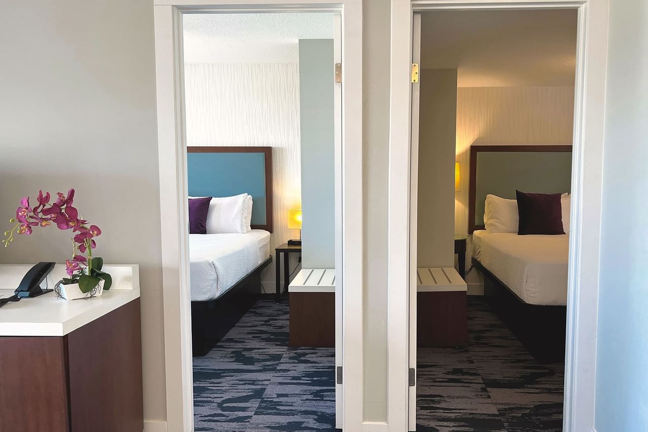 Adjoining guest rooms with carpeted floors and double beds with cushions