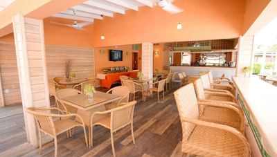 Wicker chairs and wooden dining tables under ceiling fans in Hott Pott Restaurant area at Worthing Court Apartment