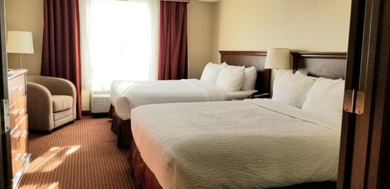 Two Queen beds with cozy chair in Standard Room at Fort McMurray Hotels