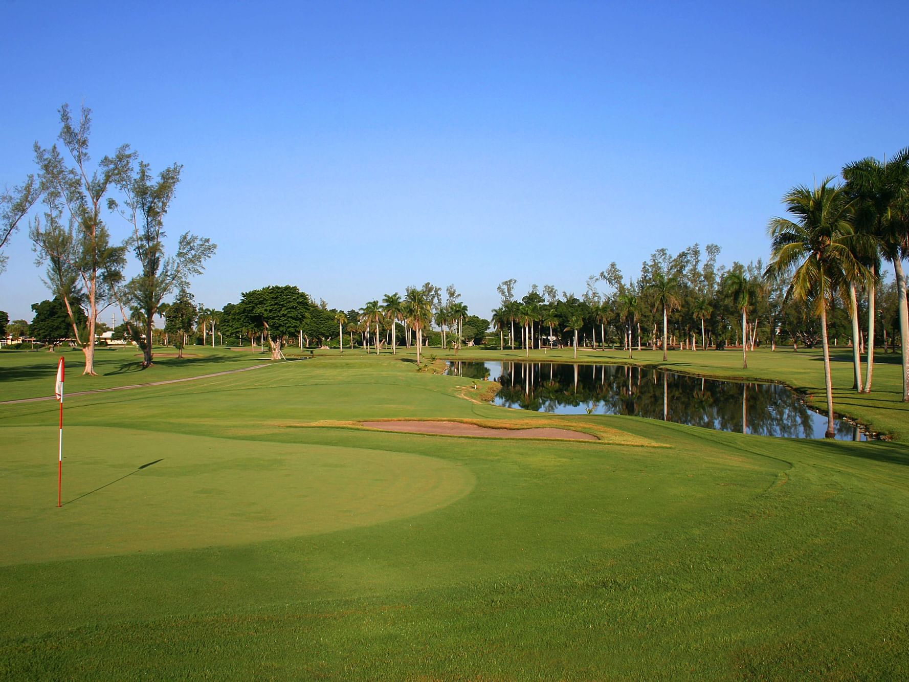 Landscape view of the golf course featuring a water pond near Miami Lakes Hotel