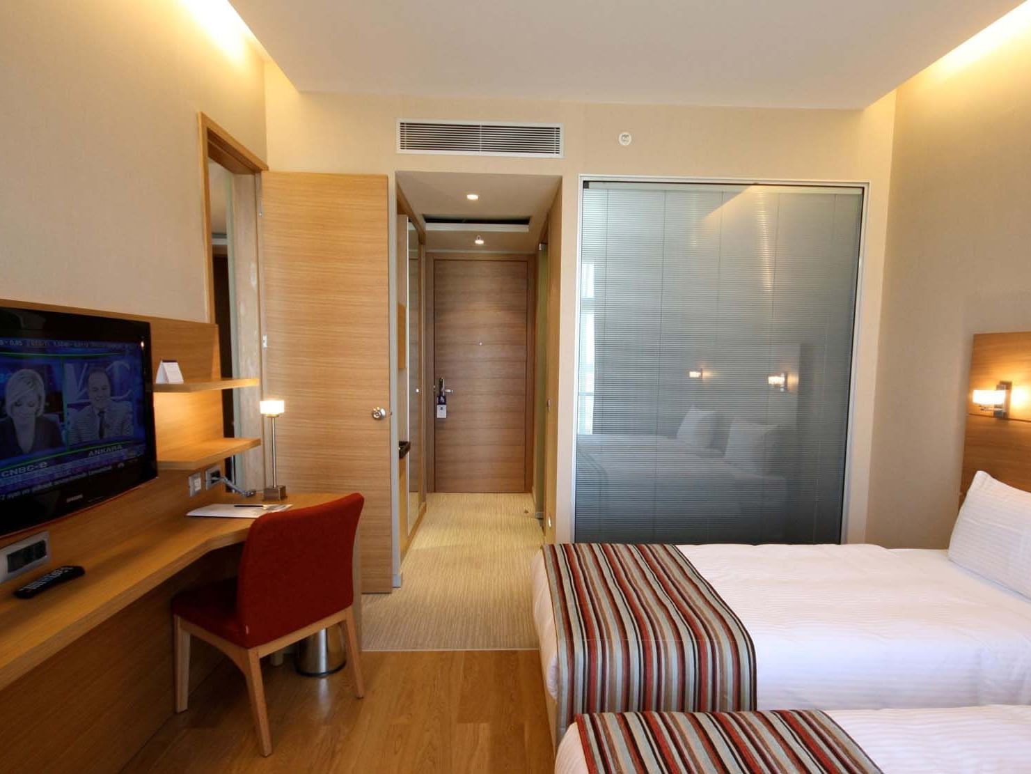 Superior Room with twin beds, desk, TV and a frosted glass bathroom door at Titanic Anadolu Gebze