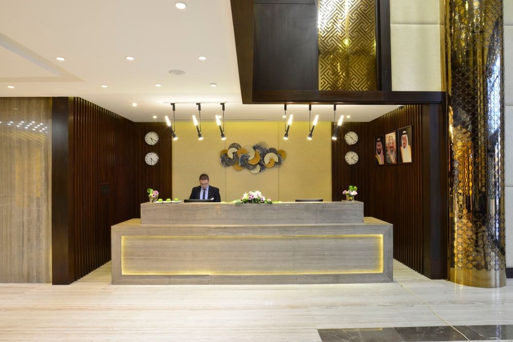 Receptionist by a desk under modern lights surrounding gold pillars at Naviti By Warwick Dammam