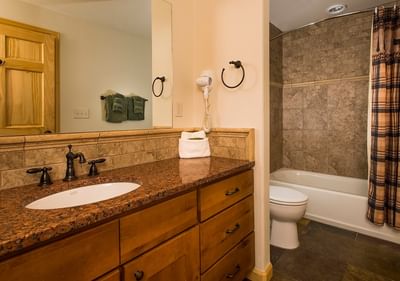 A traditional bathroom at The Stanley Hotel with a granite vanity, a tiled shower, and a large mirror