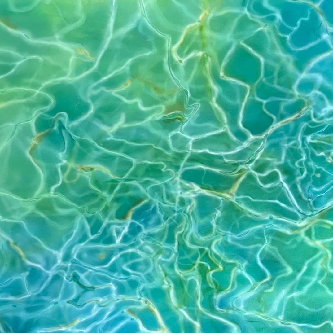 Clear turquoise water with rippling light patterns creating abstract reflections on the surface.